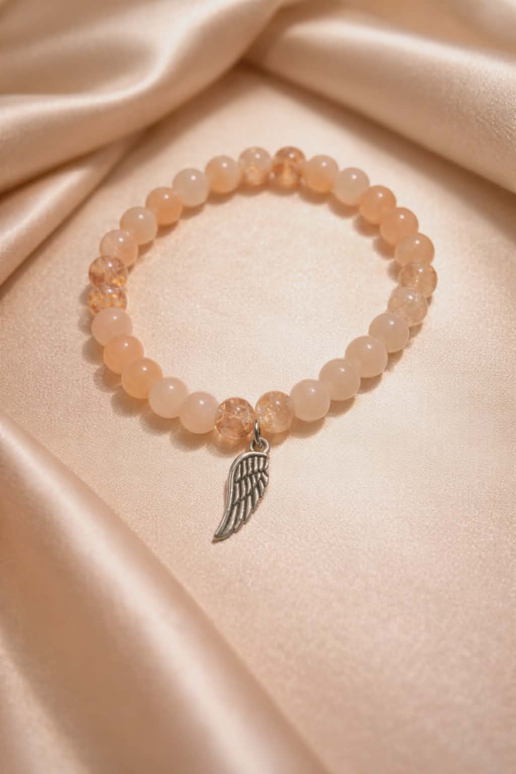 Peach beads with a wing charm handcrafted glass bead bracelet