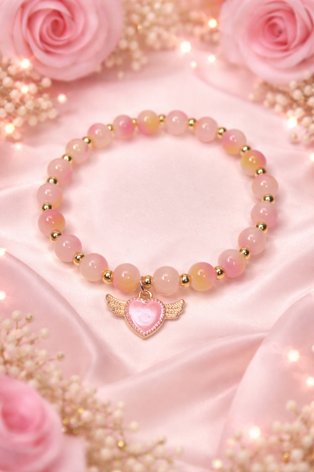 Two tone pink glass bead bracelet, gold spacers with a winged pink heart charm