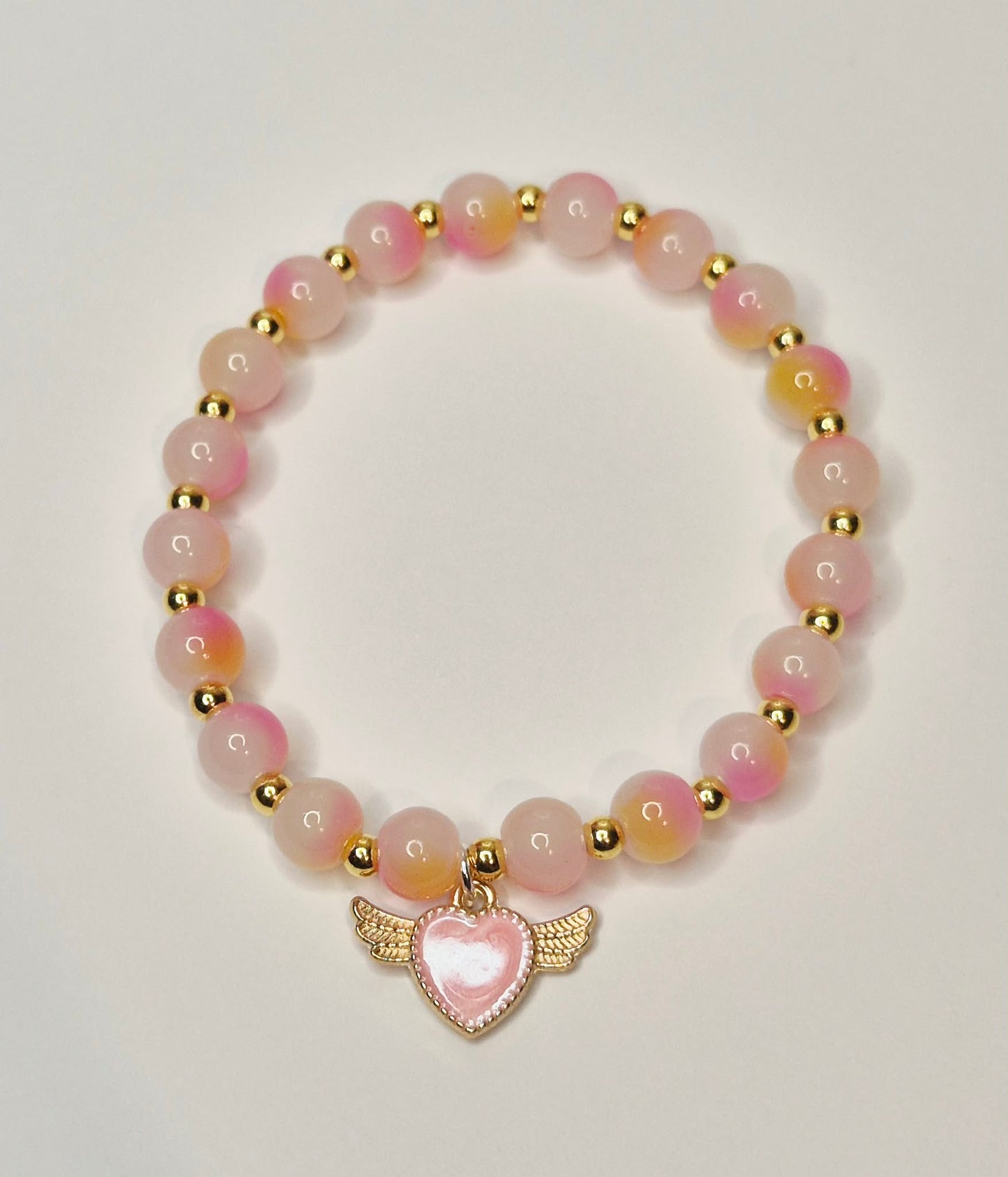 Two tone pink glass bead bracelet, gold spacers with a winged pink heart charm